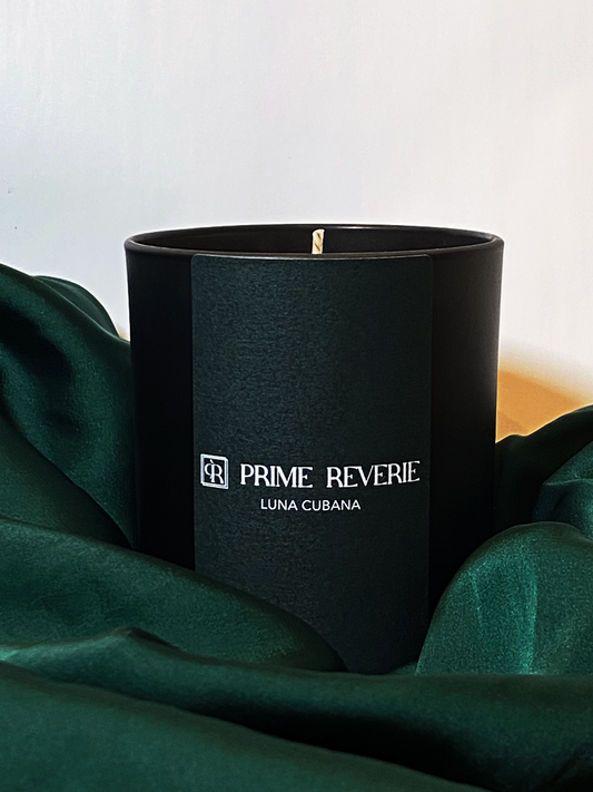 LUNA CUBANA Candle by Prime Reverie – prabangi juoda žvakė su muskuso, žaliosios citrinos, mėtų, vetiverijų ir vilkdalgių natomis neutraliame fone, demonstruojanti eleganciją ir sodrų, kviečiantį aromatą.